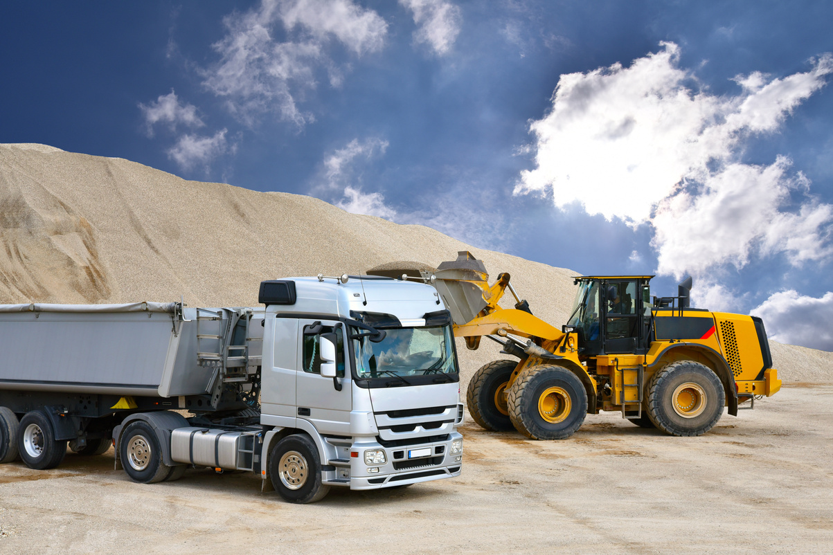 Wheel loader loads a truck with sand in a gravel pit