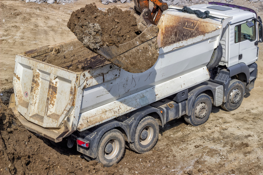 excavator bucket full of dirt and truck